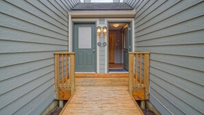 A wooden deck leading to a house with a green door and a number '65' on the wall. - Powderidge 60: Slope Side, Fireplace, Spacious Deck (Snowshoe)