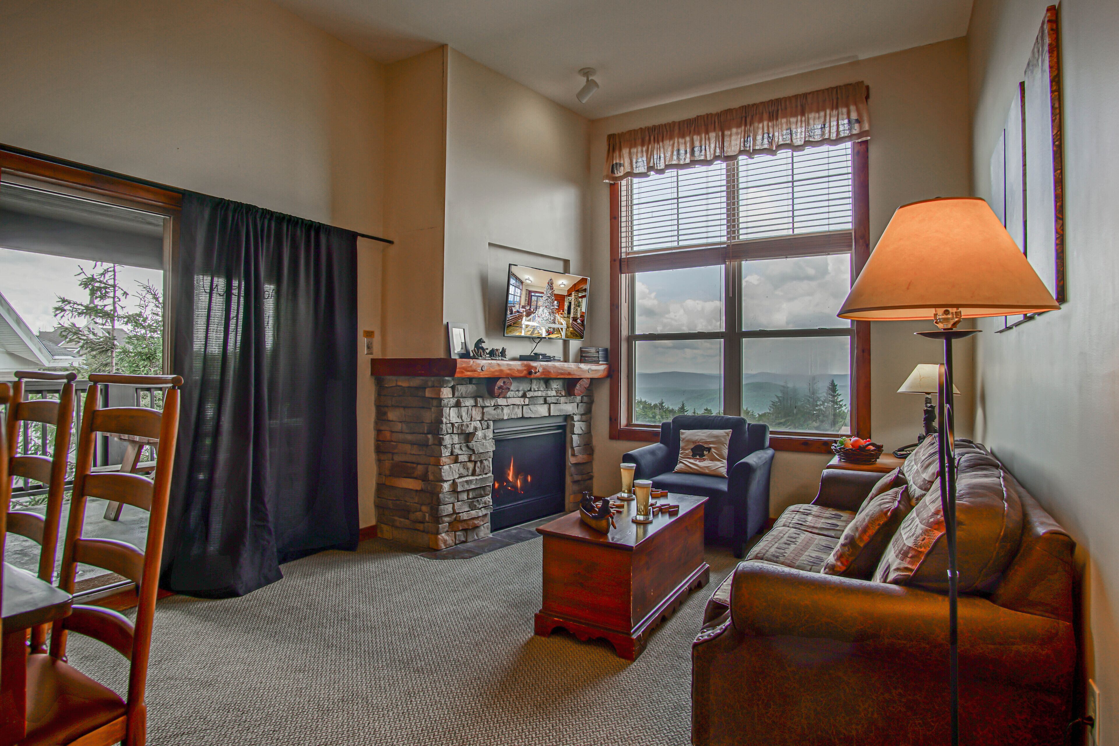 A cozy living room with a fireplace, a sofa, a coffee table, and a lamp.