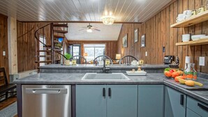 A modern kitchen with wooden paneling, a stainless steel dishwasher, a sink, and a countertop with various items. - 2 Br: Wabasso 5: 2br, 2 Bath (Snowshoe)