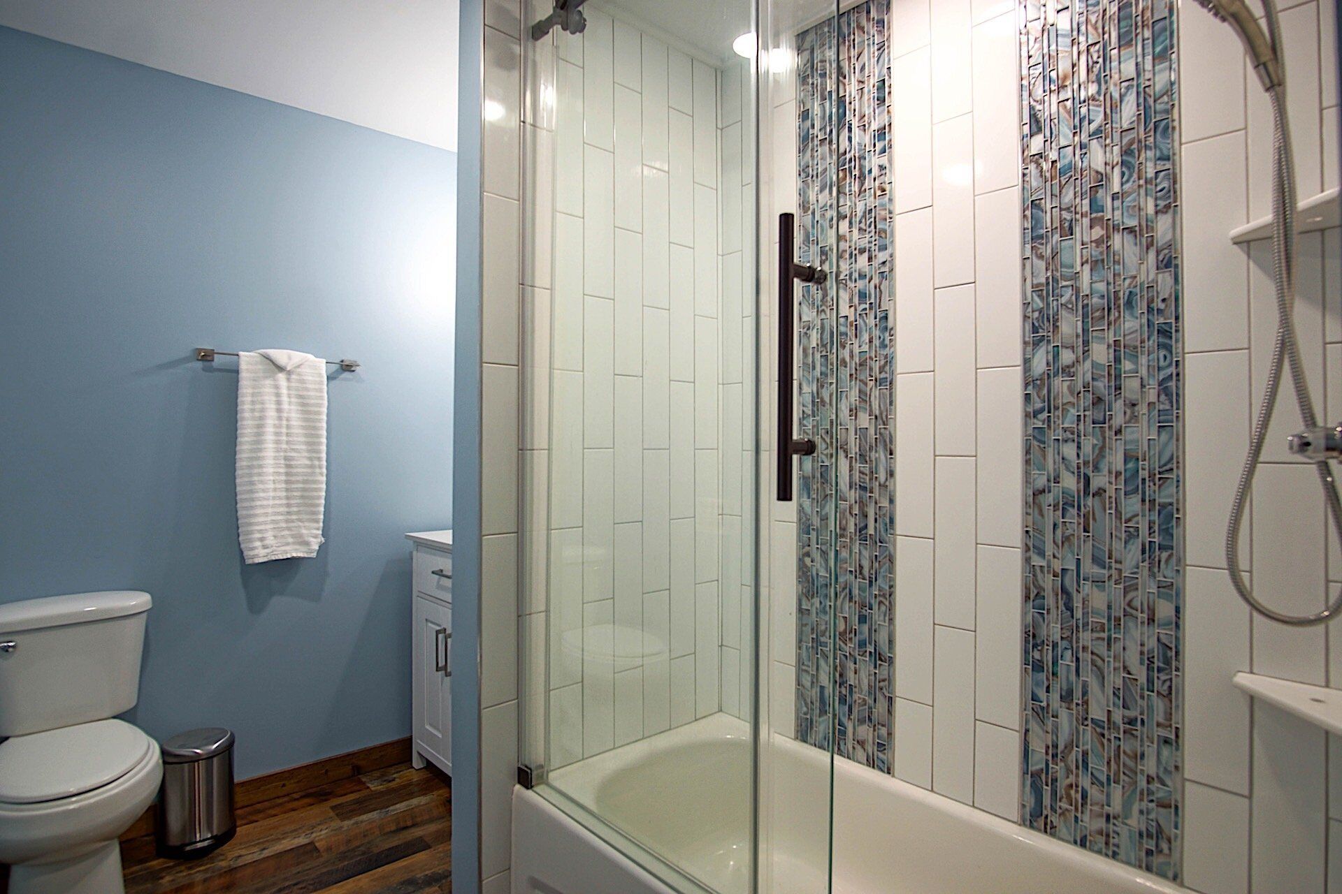 A bathroom with a glass-enclosed shower, a white bathtub, and a toilet.