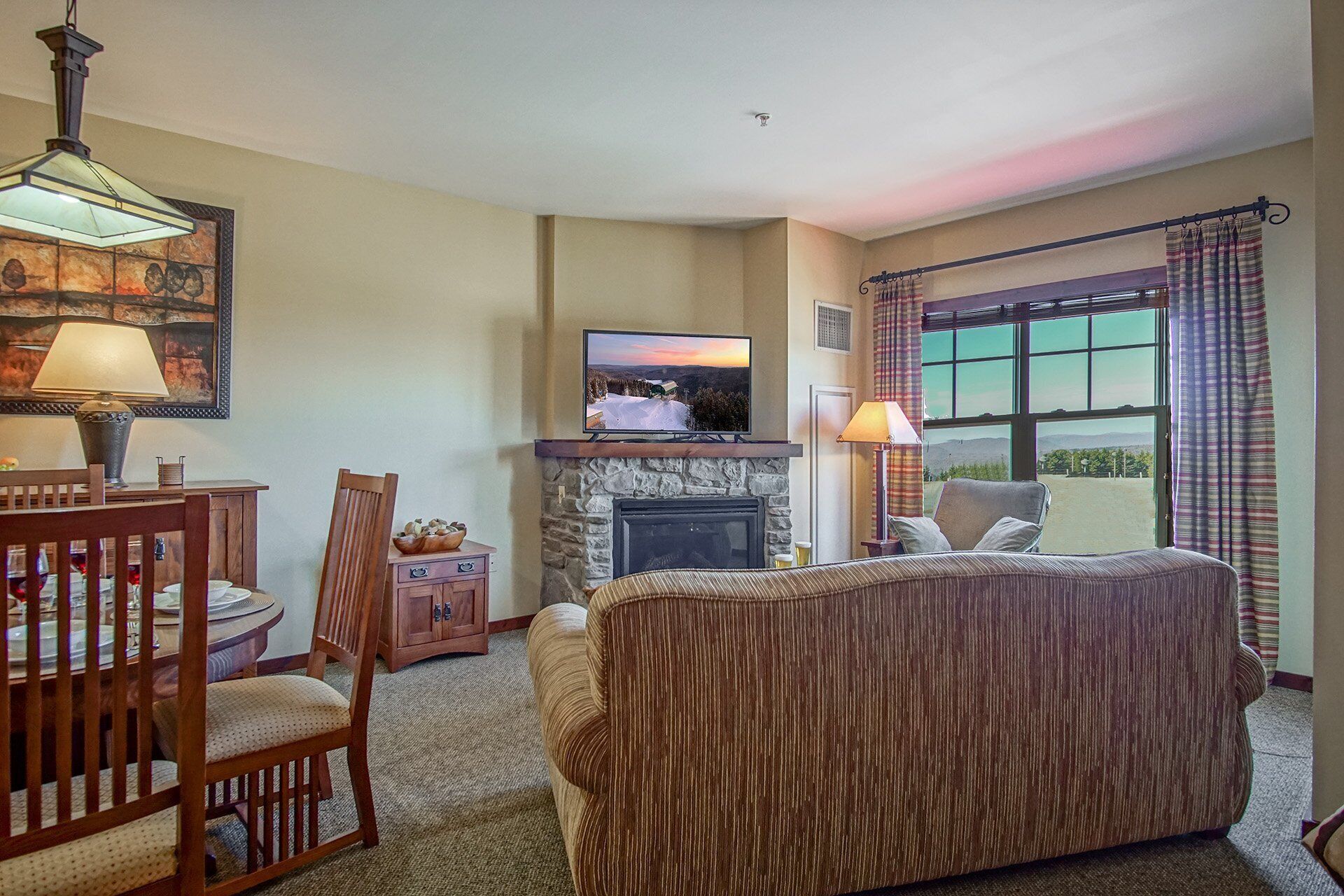 Un salón acogedor con chimenea, televisión y vistas al exterior.