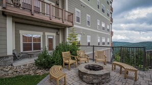 Un patio con mobiliario exterior, una fogata y vistas de una cadena montañosa.