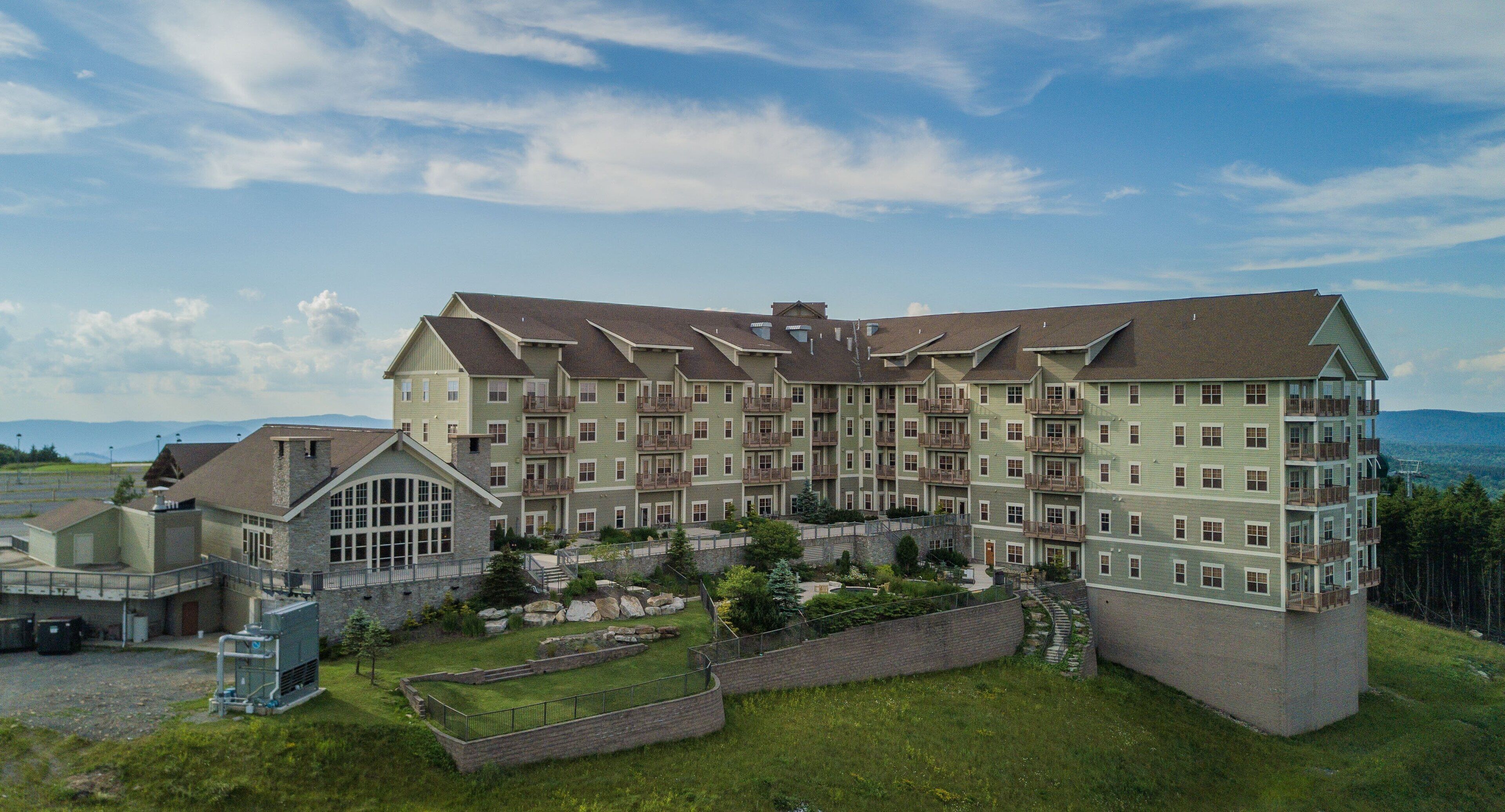 Un hotel a più piani con un cortile centrale, balconi e vista sul paesaggio circostante.