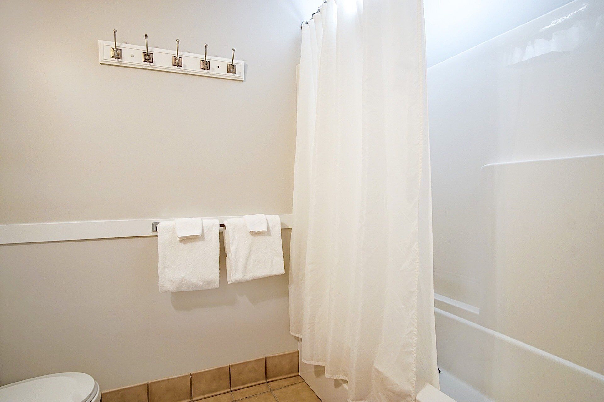 A bathroom with a shower curtain, a towel rack with two towels, and a toilet.