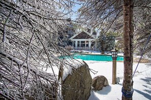 A snow-covered landscape with a pool, a wooden deck, and a building with a white facade and large windows. - Ski In/out! 1 Bed 1 Bath Slope Views Allegheny Springs 238 (Snowshoe)