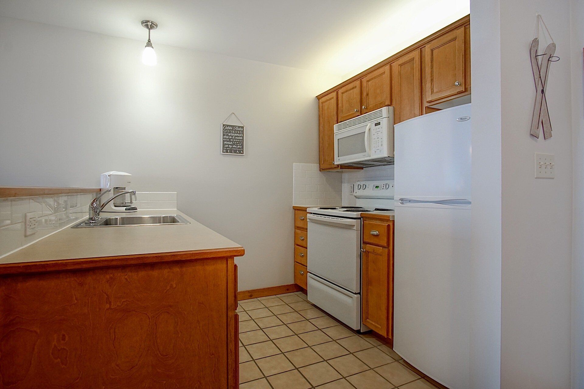 A compact kitchen with wooden cabinets, a microwave, a stove, and a refrigerator.