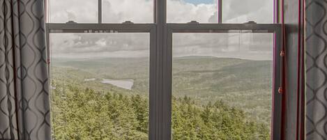 A room with a large window offering a view of a forested landscape.