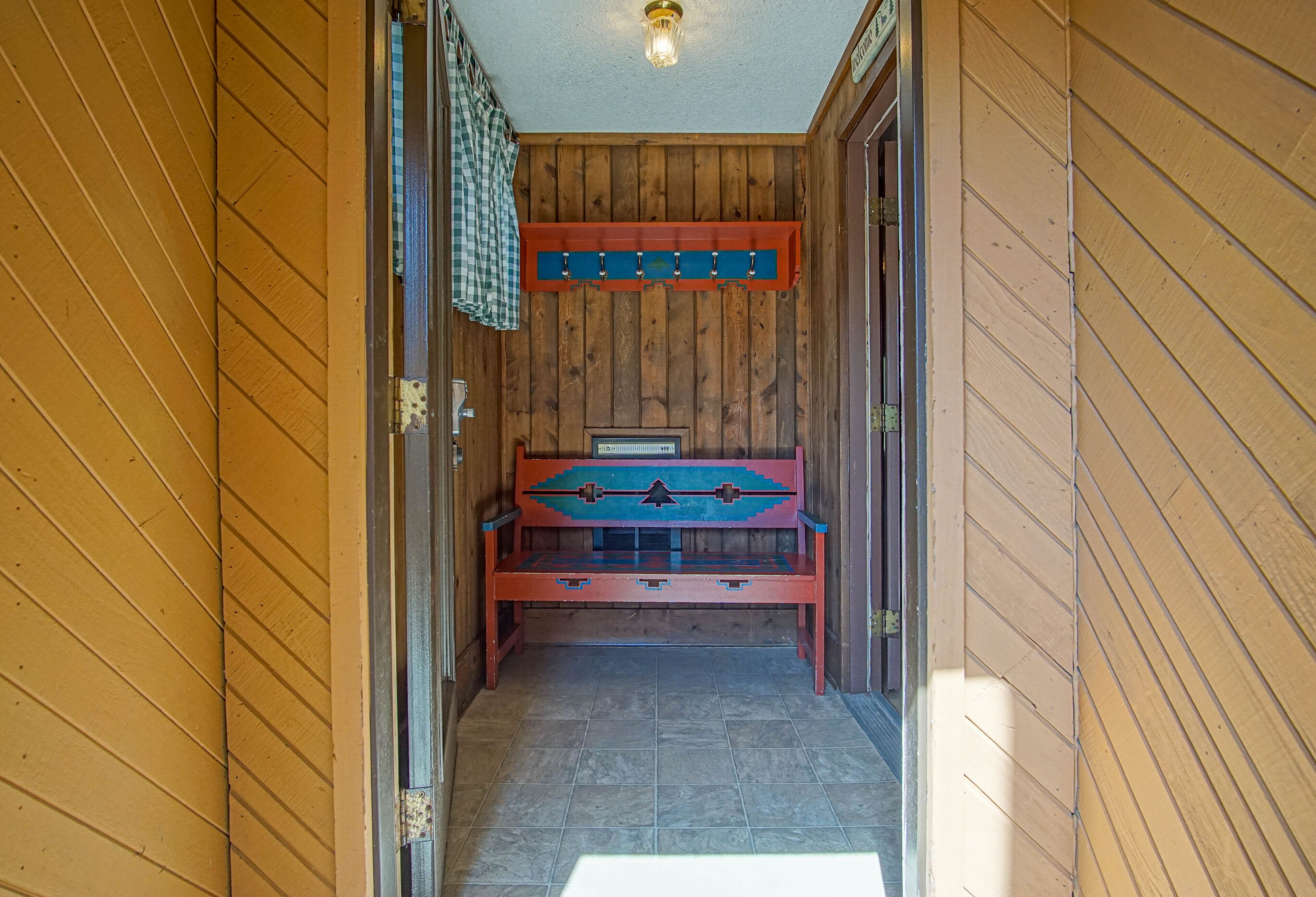 Un couloir intérieur en bois, avec un banc et un porte-manteau.