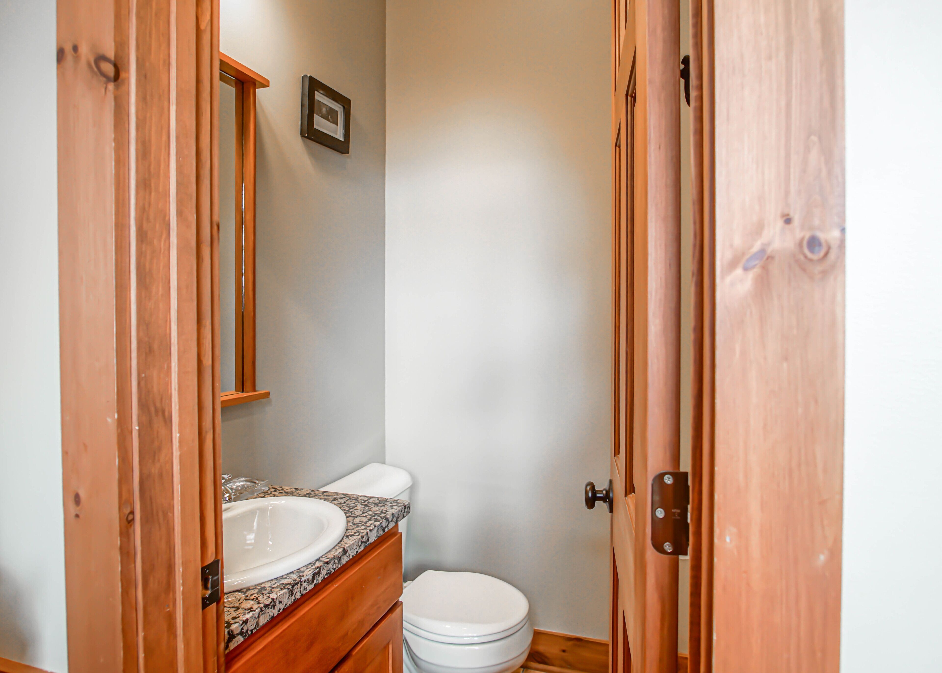 A small bathroom with a wooden vanity, a sink, and a toilet.