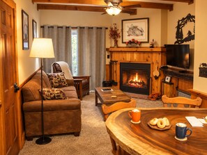 A cozy living room with a fireplace, a sofa, a coffee table, and a television. - Whistlepunk 45- Modern Comfort With Mountain Charm-1 Bedroom (Snowshoe)