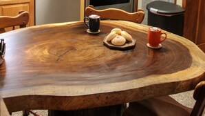 A wooden dining table with a coffee mug, a plate of donuts, and a red mug. - Whistlepunk 45- Modern Comfort With Mountain Charm-1 Bedroom (Snowshoe)