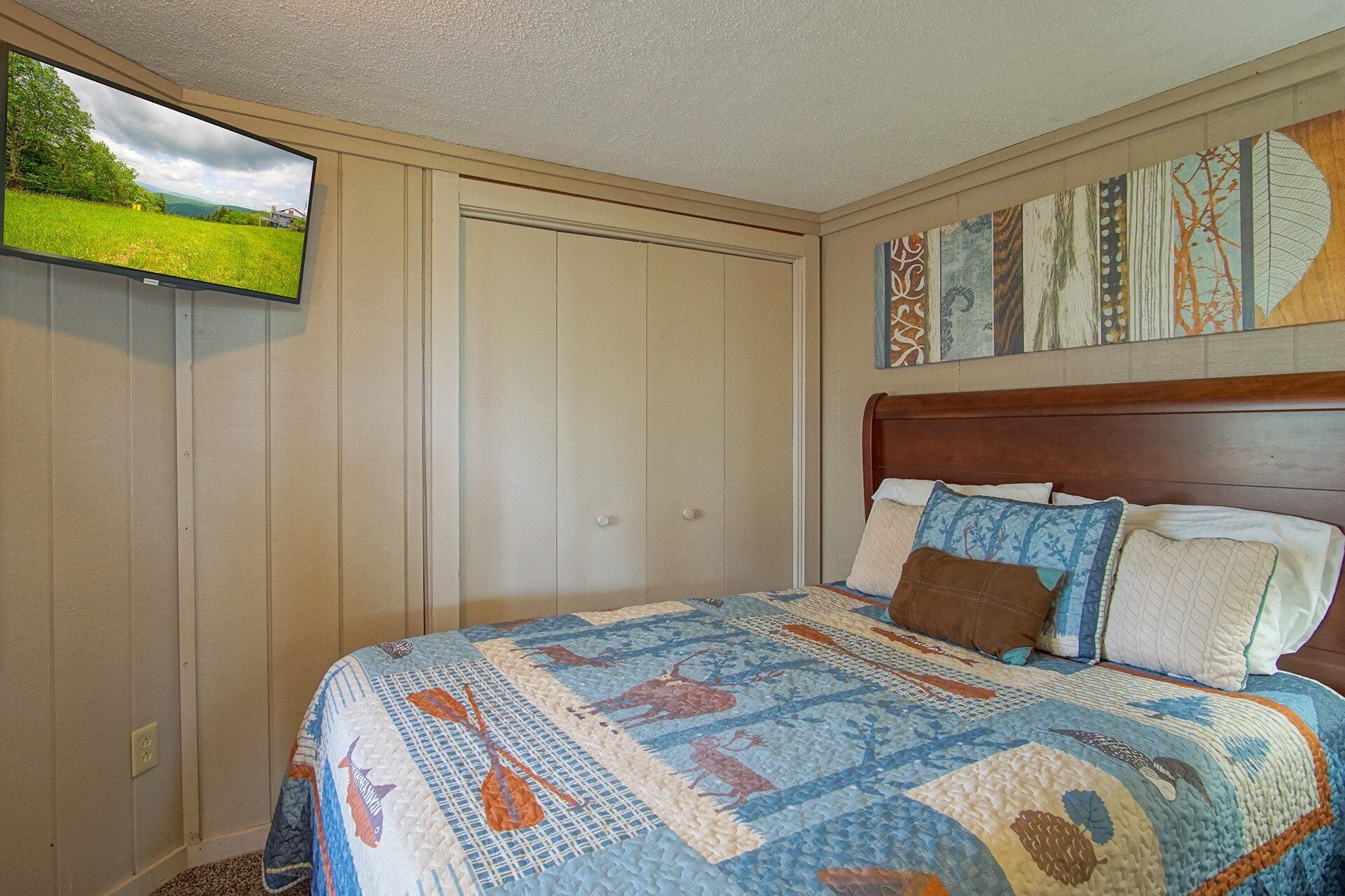 A bedroom with a bed, a TV mounted on the wall, and a door.