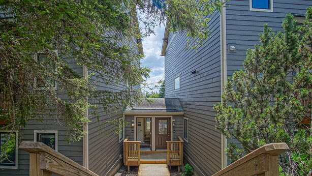A wooden staircase leading to a front door with a porch, flanked by two windows and a door number 43. - Powderidge 44: 1br: 1 Bath Flat (Snowshoe)