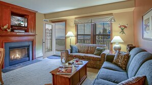 Una sala de estar acogedora con chimenea, televisor y un balcón con vistas.