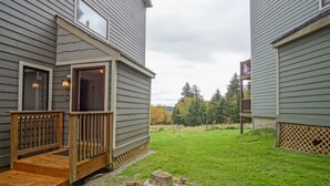 A residential building with a wooden deck and a grassy yard. - 1 Br: Powderidge 30:slope Side, Pet Friendly end Unit on Shuttle Route (Snowshoe)