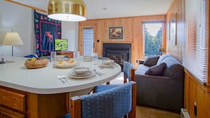 A cozy interior with a round dining table set for four, a sofa, and a fireplace. - 1 Br: Powderidge 30:slope Side, Pet Friendly end Unit on Shuttle Route (Snowshoe)