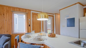 A compact kitchen with wooden paneling, a white countertop, a built-in sink, and a dining area with a round table and chairs. - 1 Br: Powderidge 30:slope Side, Pet Friendly end Unit on Shuttle Route (Snowshoe)