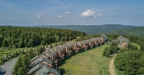 A row of log cabin-style buildings with a central walkway, surrounded by forested hills. - 1 Br: Powderidge 30:slope Side, Pet Friendly end Unit on Shuttle Route (Snowshoe)
