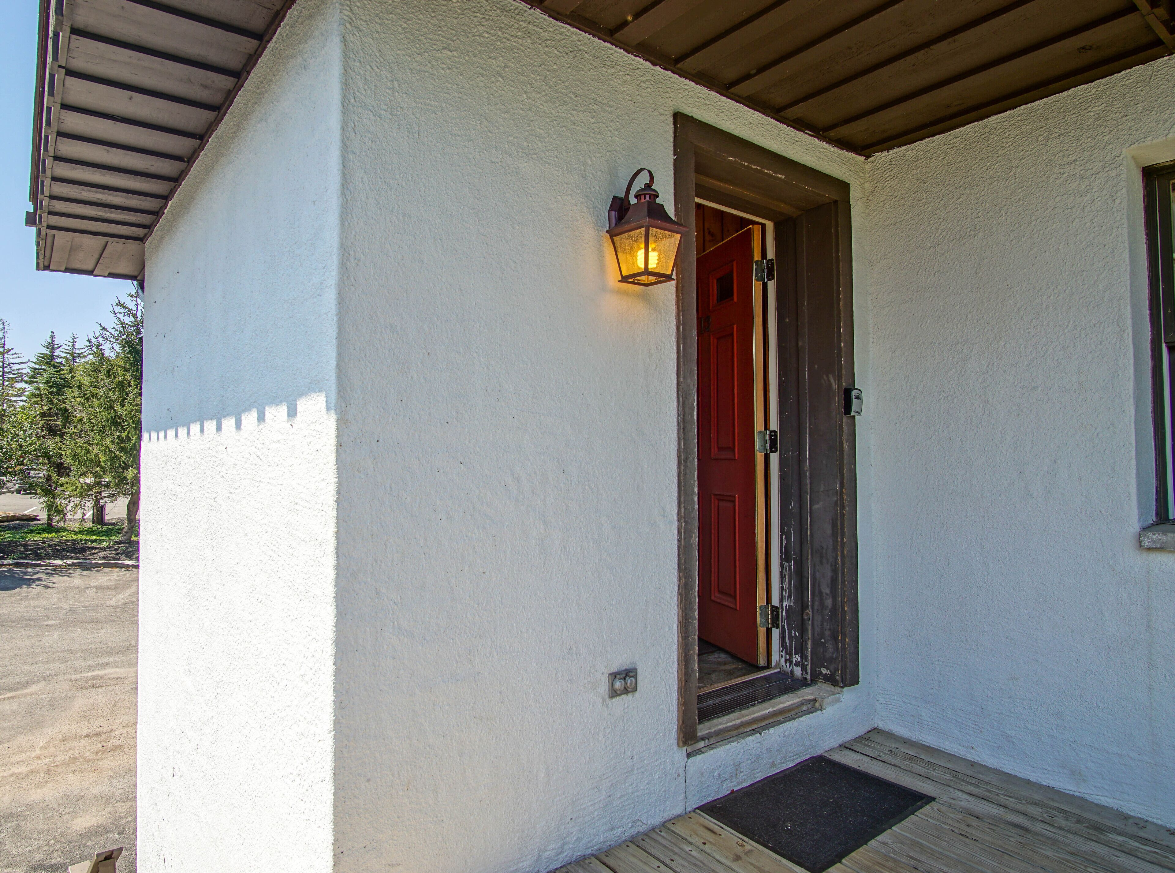 A white building with a red door and a wooden porch.