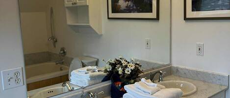 A bathroom with a double sink, a large mirror, and two framed paintings.