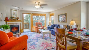 A spacious living room with a fireplace, a ceiling fan, and a dining area with a table set for a meal. - Camp 4 #21: 2 Bedrooms, 2.5 Baths: Slope Side, Gas Fireplace (Snowshoe)