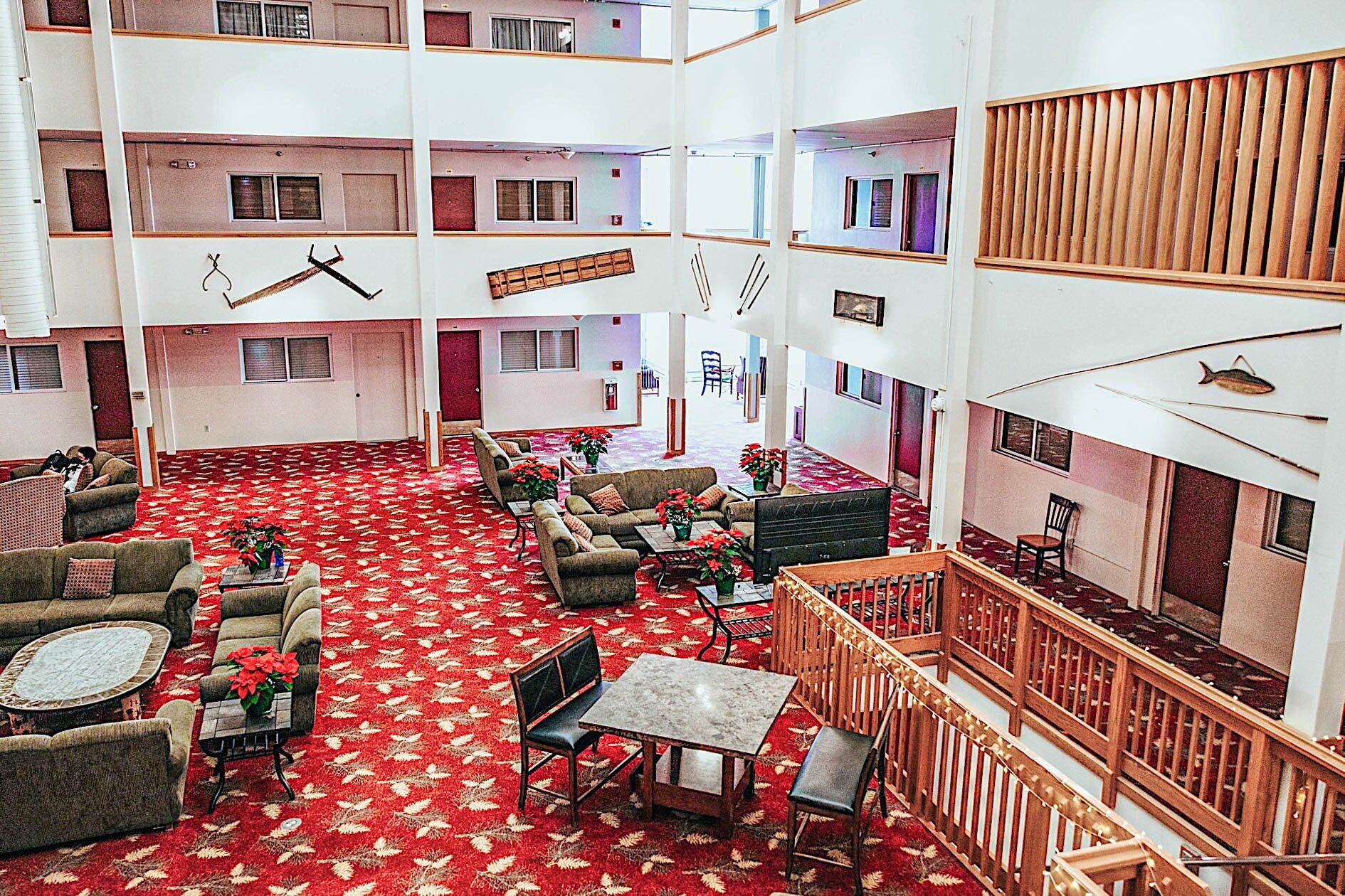 Un hall d’hôtel à plusieurs niveaux, doté d’un tapis rouge à motifs, de plusieurs espaces aménagés pour s’asseoir et d’une balustrade en bois donnant sur le niveau inférieur.