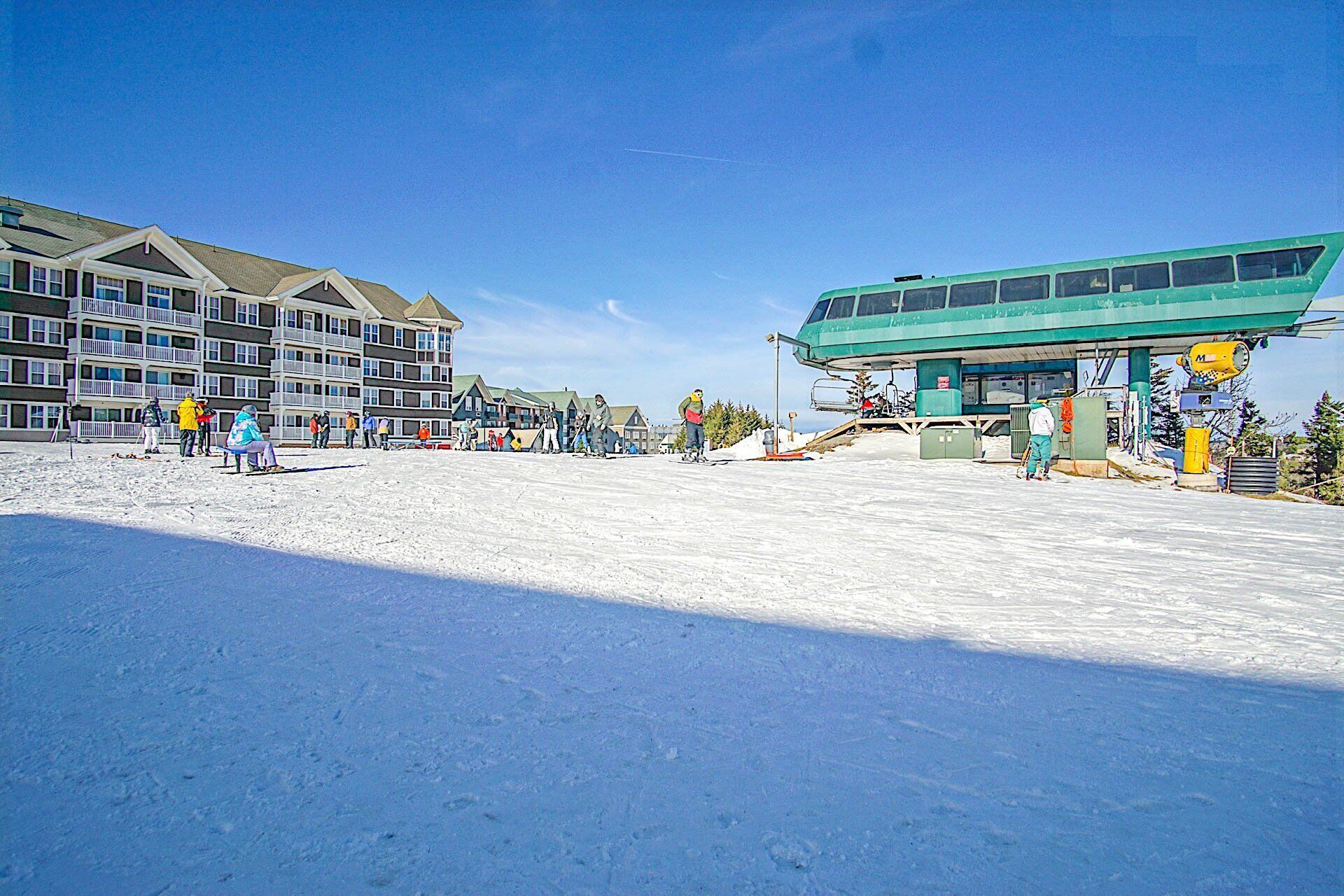 A ski resort with a multi-story building, ski lift, and snow-covered ground.