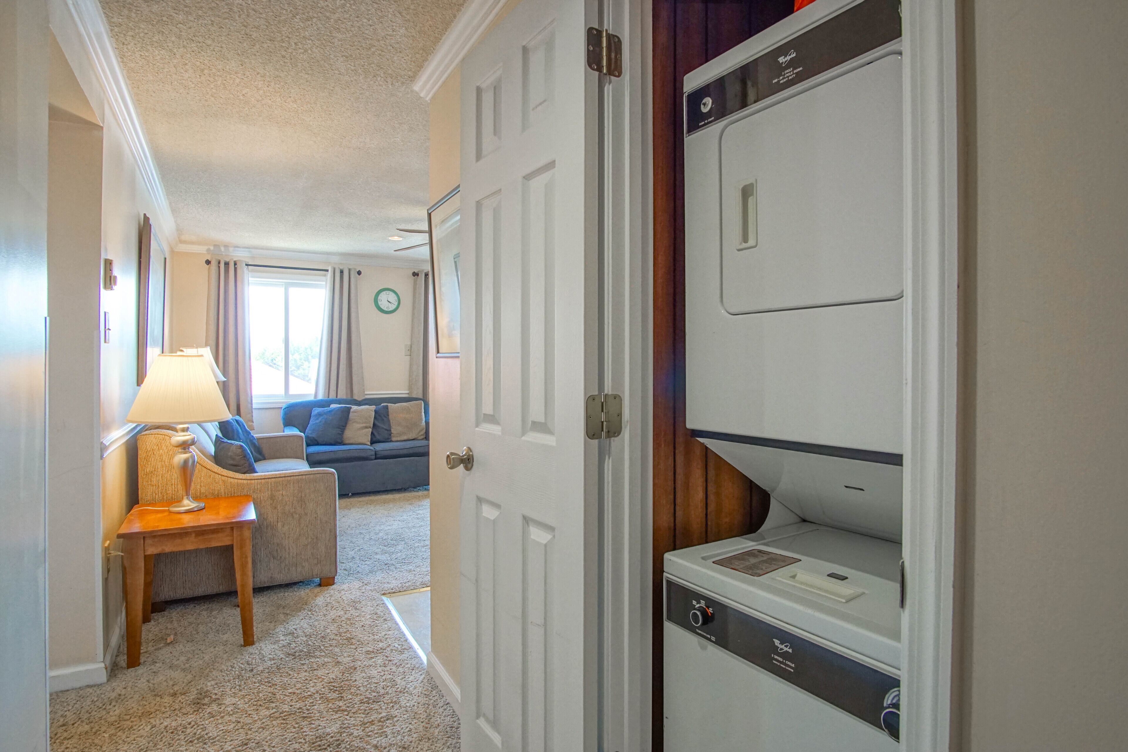 A hotel room with a seating area, a door leading to a laundry room, and a visible clock on the wall.