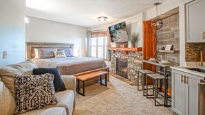 A bedroom with a large bed, a bench, a fireplace, and a view of a pool. - Rimfire 421 Cozy Studio Just Steps From the Village Slope Side (Snowshoe)