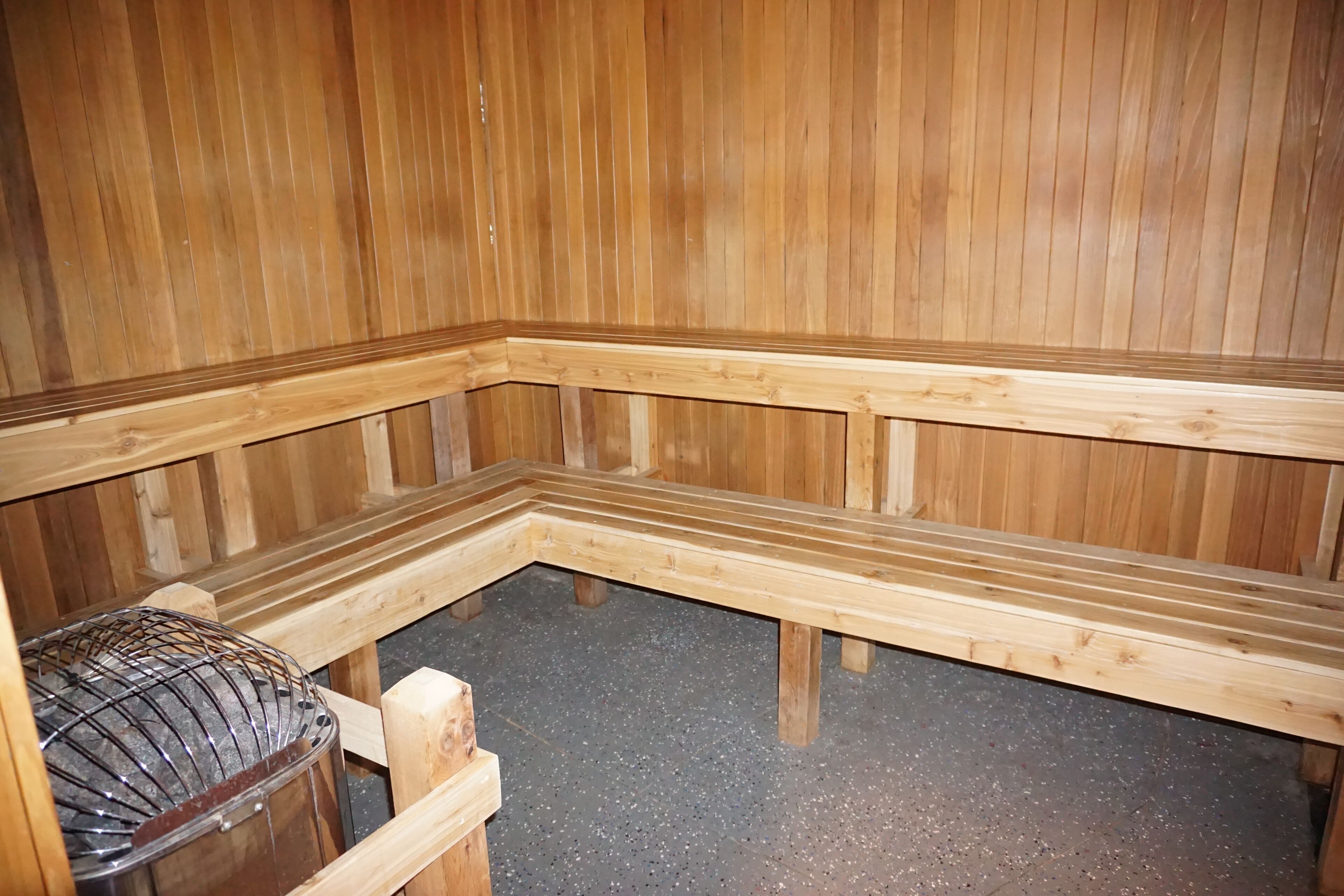 A wooden sauna with benches and a metal bench.