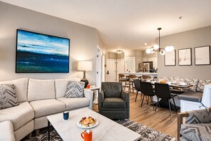 A modern living room with a sofa, coffee table, and a dining area with chairs and a table. - 2 Br Seneca Condo 200 Beautiful Vista Views (Snowshoe)
