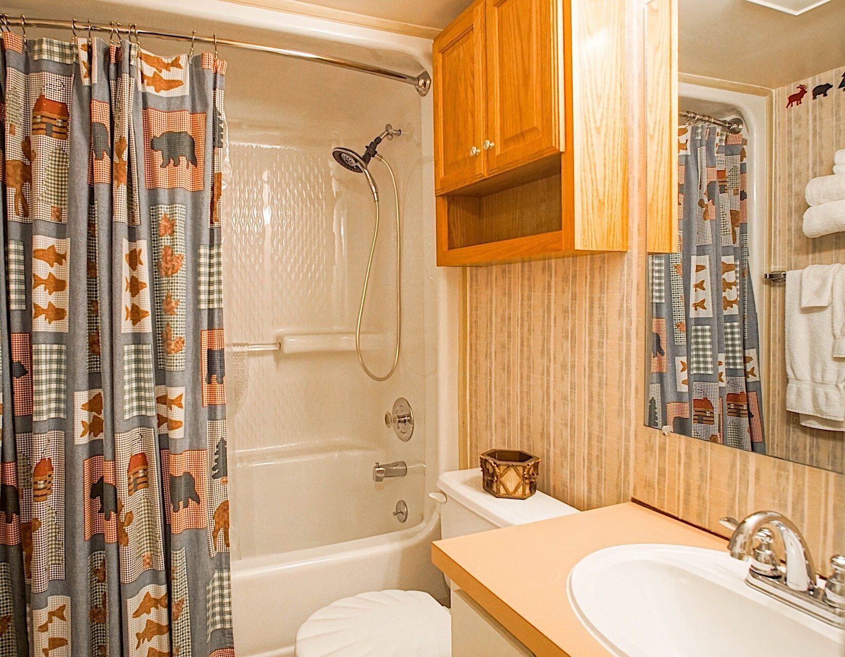 Un baño con ducha, inodoro, lavabo y armario de madera.