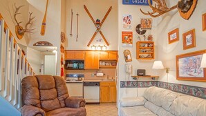 A cozy living room with a brown leather armchair, a light-colored sofa, and a kitchen in the background. - Silver Creek 5216 - The Winter`s Amazing 2 Br Condo (Snowshoe)
