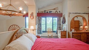 A bedroom with a bed, a wooden dresser, a chair, a window with curtains, and a chandelier. - Silver Creek 5216 - The Winter`s Amazing 2 Br Condo (Snowshoe)