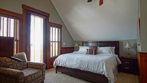 A bedroom with a large bed, a chair, a nightstand, and a ceiling fan.