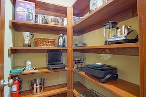 A kitchen with wooden shelves holding various appliances and kitchenware.