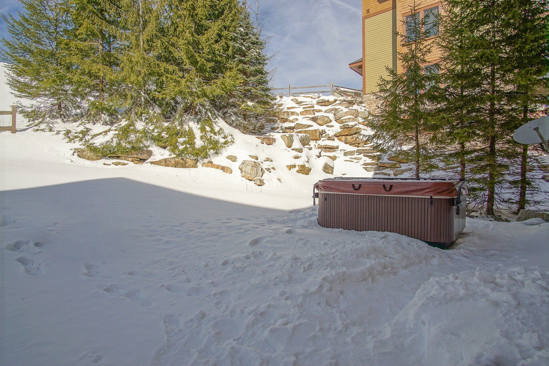 Zona exterior cubierta de nieve con un jacuzzi y un edificio al fondo.