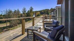 A wooden deck with outdoor seating, overlooking a forested area and a road. - 3 Bedroom: Coal Box Beautiful Unique Home Close to Slopes (Snowshoe)