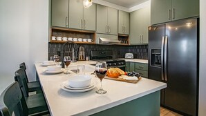 A modern kitchen with green cabinets, a black refrigerator, a built-in oven, and a white countertop. - 3 Bedroom: Coal Box Beautiful Unique Home Close to Slopes (Snowshoe)