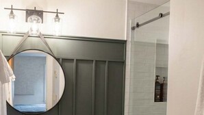 Un baño con inodoro, lavabo con espejo y zona de ducha.