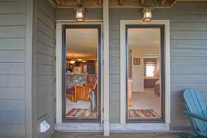 A wooden exterior with a sliding glass door leading to a living area with a sofa, a coffee table, and a lamp. - Powderidge #31: 2 Bedrooms, 2 Full Baths: Slope Side, Wood Fireplace (Snowshoe)