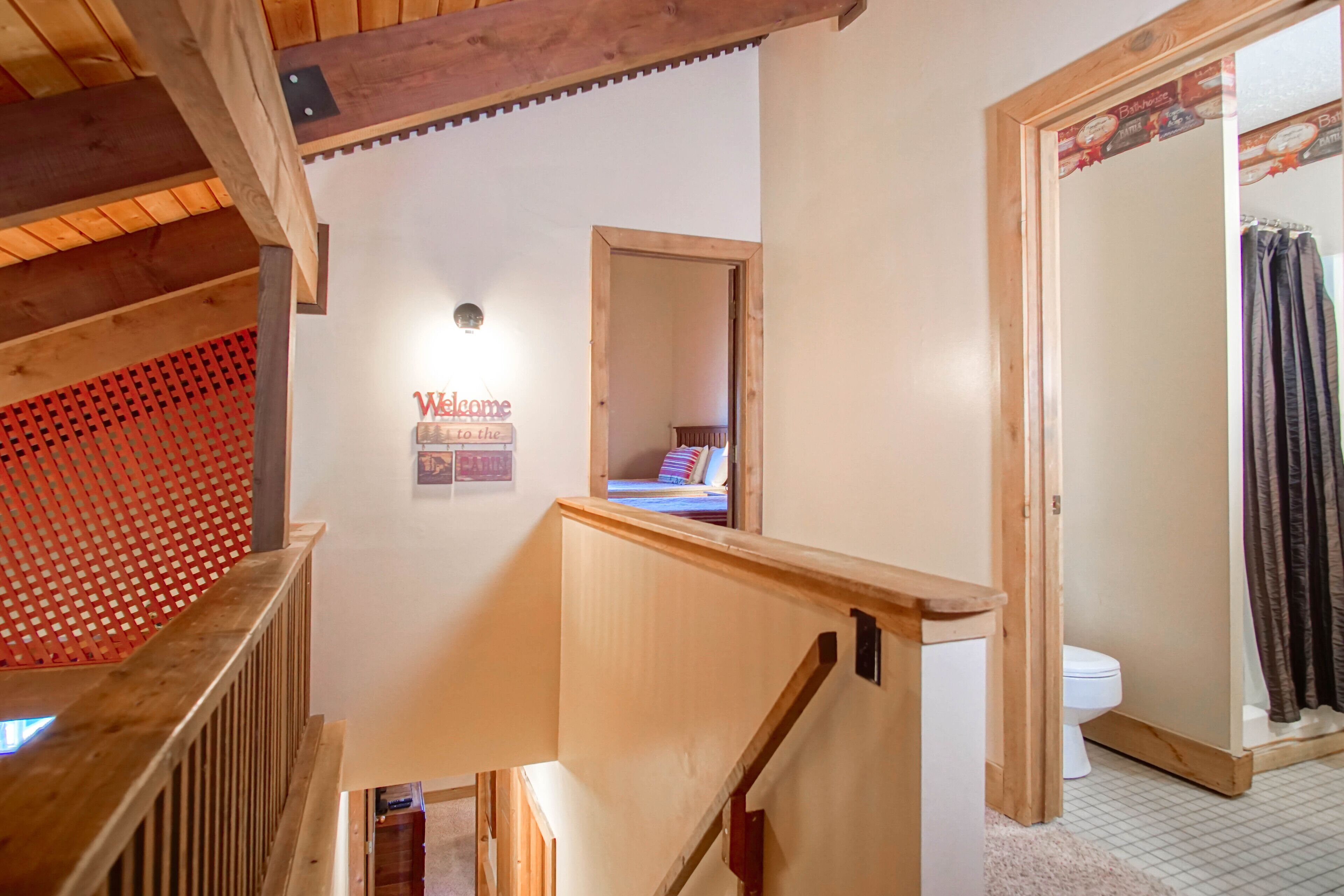 Una escalera de madera que lleva a un dormitorio con una cama y un cartel que dice 'Welcome'.
