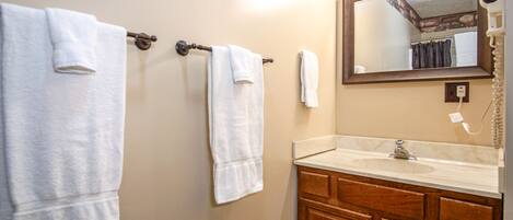 A bathroom with two towels hanging on a towel rack, a sink, and a mirror with lights above it.