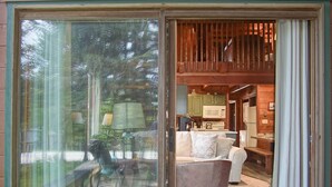 A cozy interior with a sliding glass door leading to a living area featuring a sofa, a coffee table, and a kitchen area with a microwave and stove. - Powder Monkey 4: 2 Bedrooms Plus Sleeping Loft, 2 Full Baths: Slope Side (Snowshoe)
