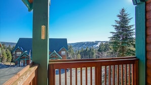 Una terraza de madera con vistas a un albergue de montaña y un bosque circundante.