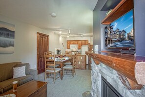 A cozy living room with a fireplace, a dining area, and a kitchen. - Rimfire 322-323: Combined 2 one Bedroom Units, Slopeside (Snowshoe)