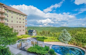 A hotel with a pool area, surrounded by lush greenery and mountains. - Soaring Eagle 414 (Snowshoe)
