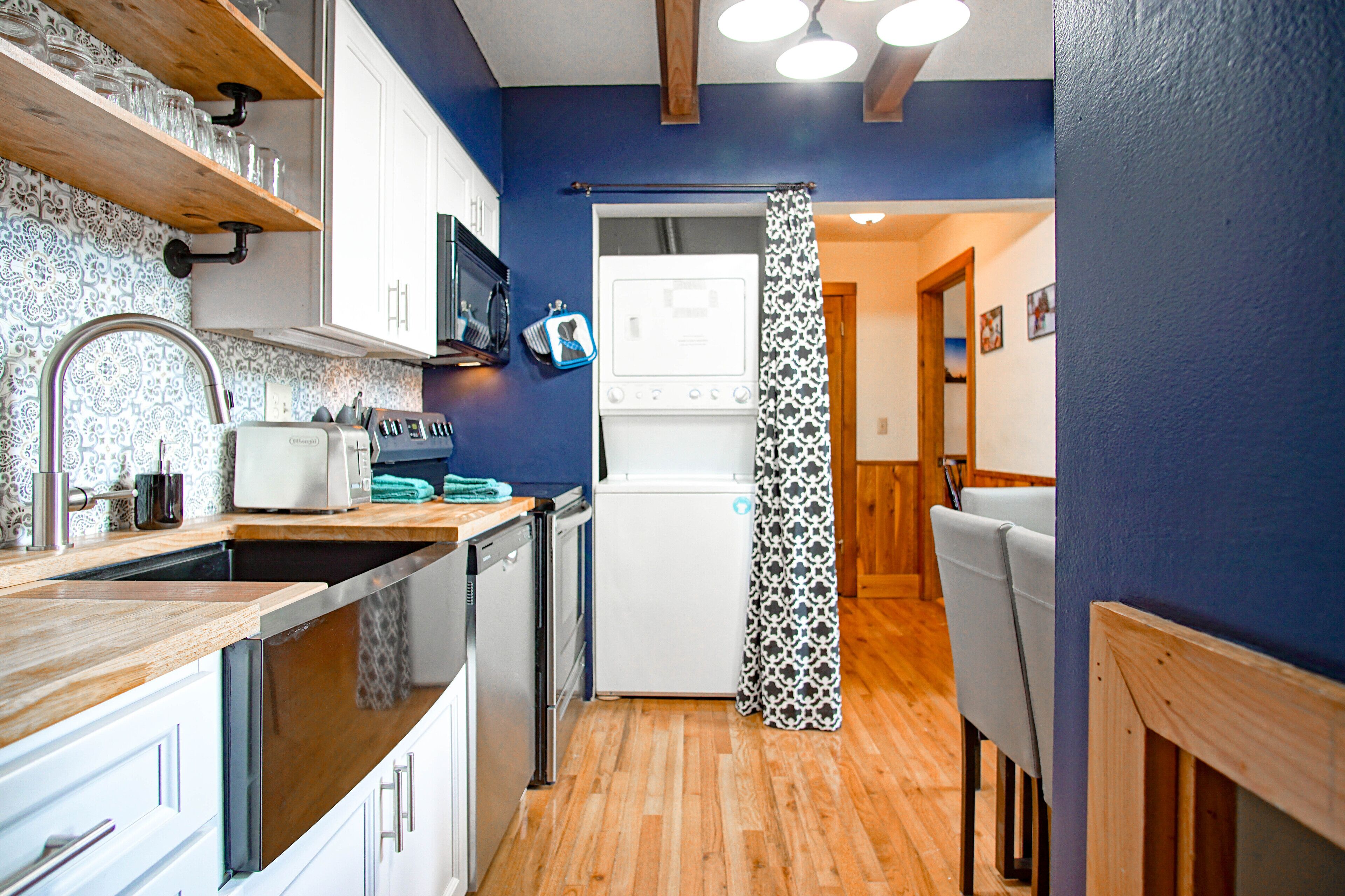 Cocina compacta con encimeras de madera, armarios blancos, microondas y refrigerador.