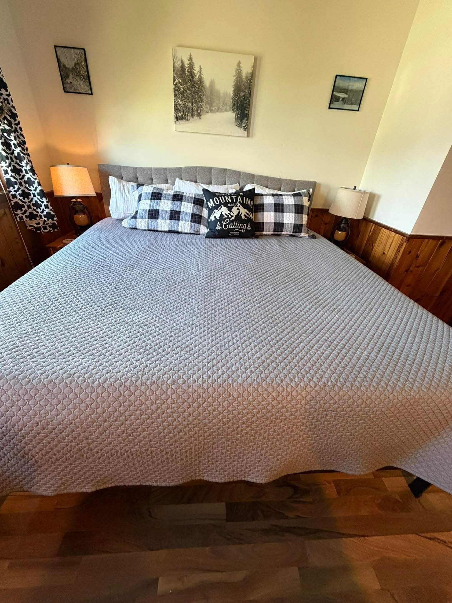 A bed with a quilted cover, a headboard, and two bedside lamps.