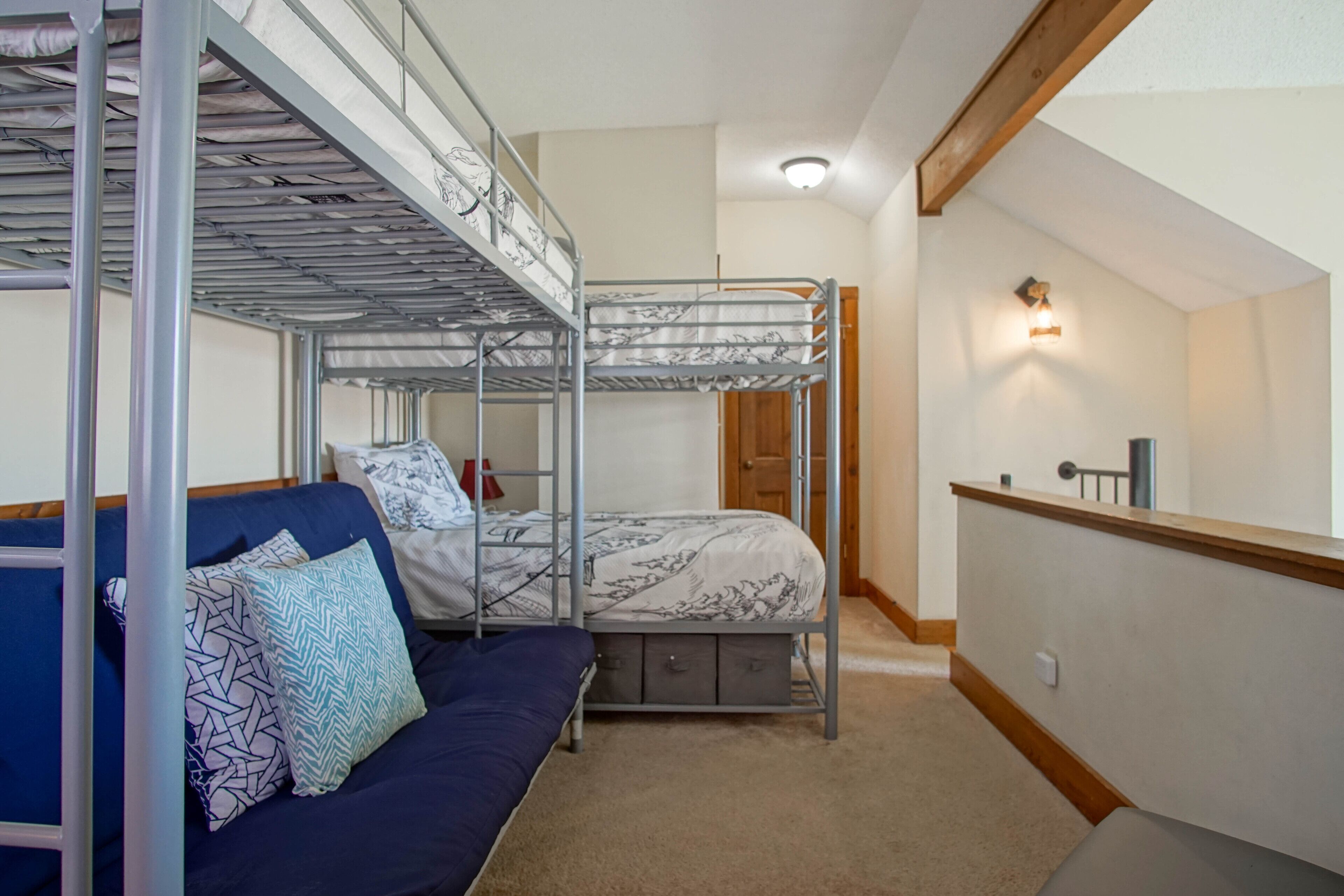 Habitación tipo dormitorio con literas, un sofá y un escritorio pequeño.